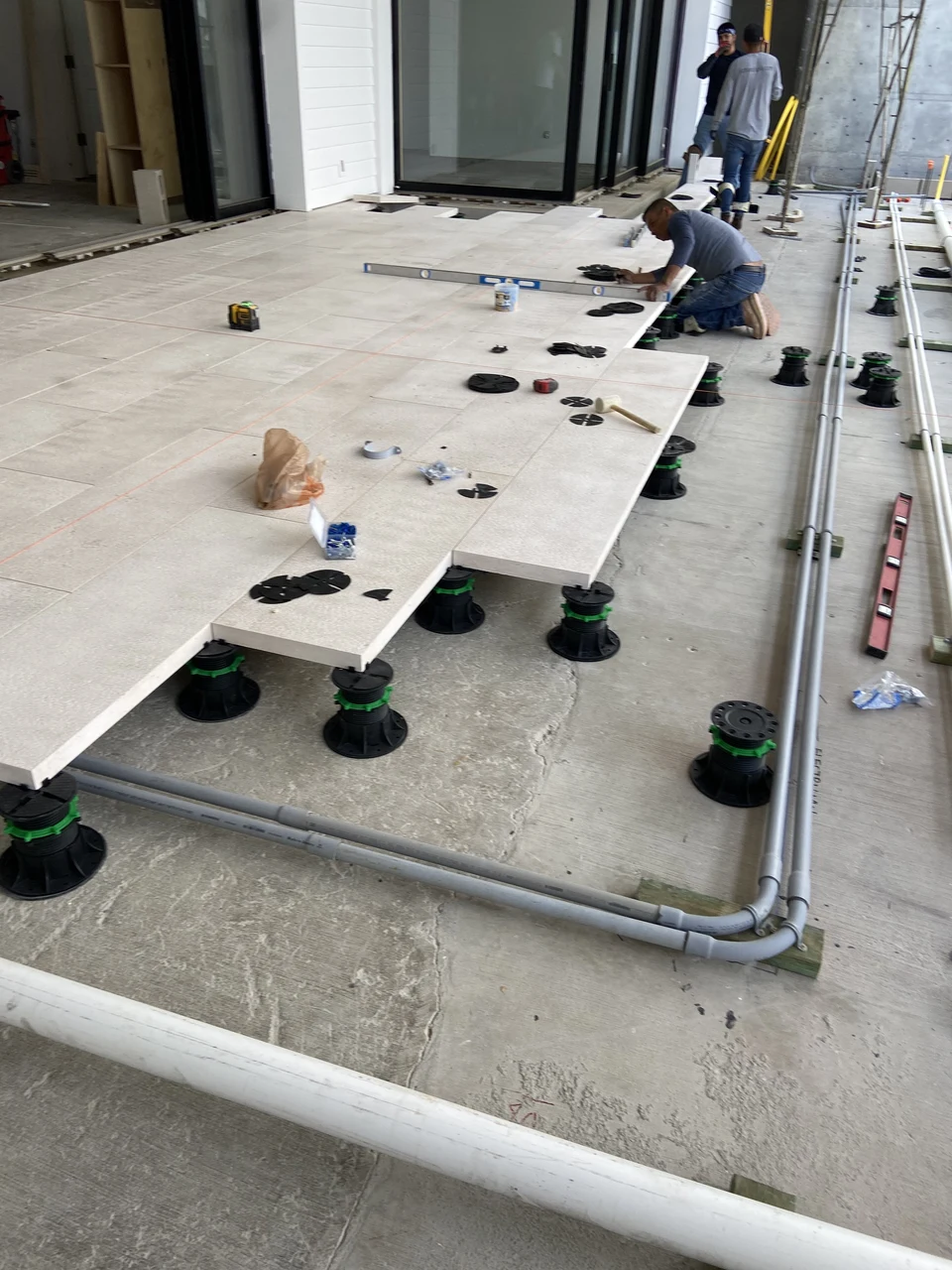Pavers resting on adjustable pedestal supports with an unfinished edge exposing the surface below