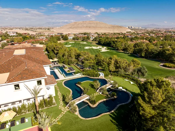 Aerial curving pool and putting green beside golf course in La Quinta