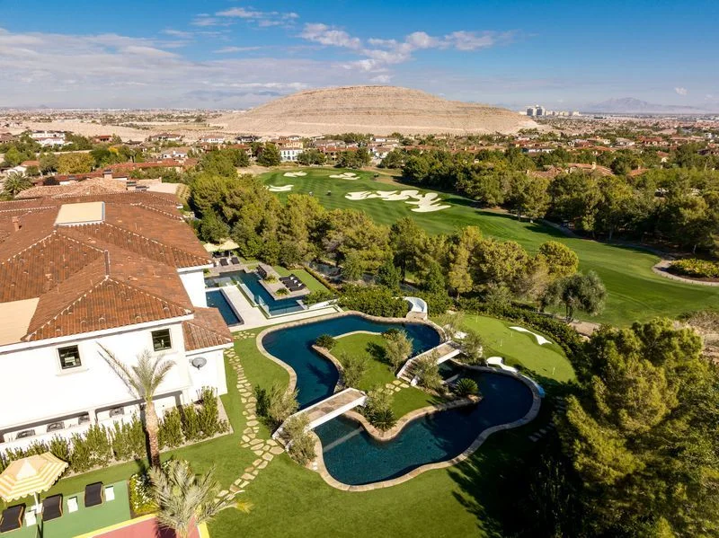 Aerial curving pool and putting green beside golf course in La Quinta