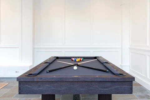 Billiards table against white paneled pool house wall