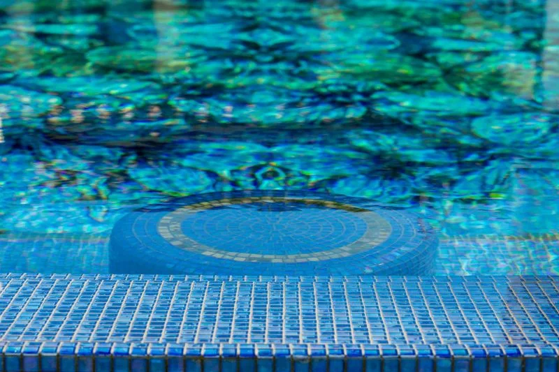 Blue glass mosaic pool tile and submerged seat in Irvine