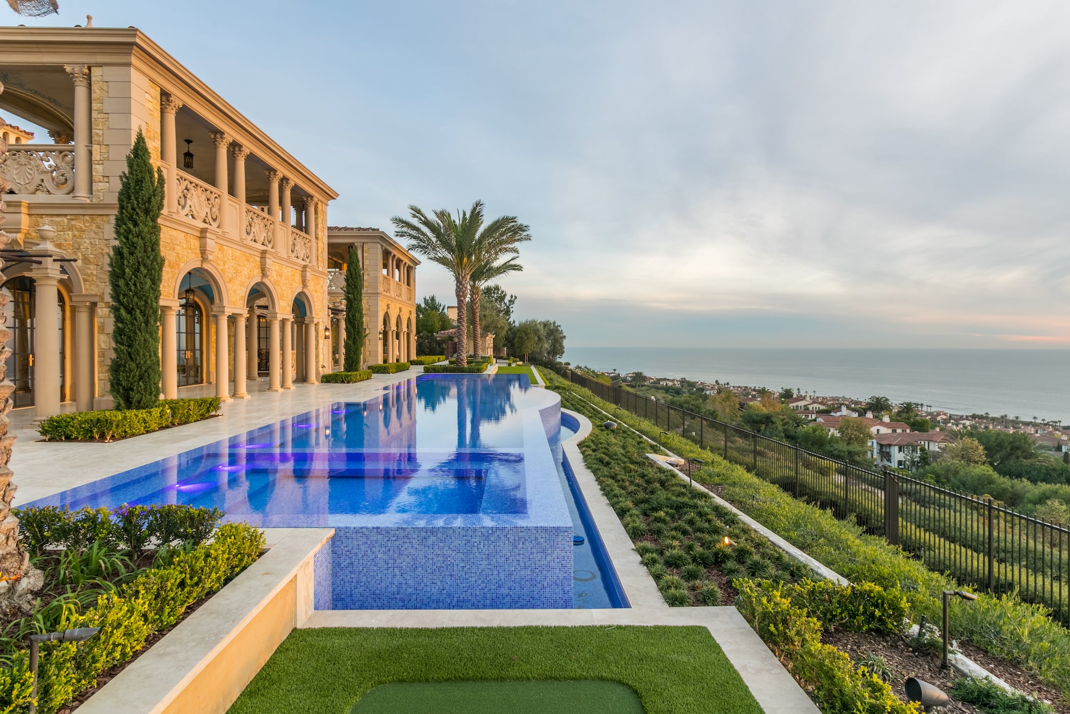 Blue tiled infinity pool beside coastal stone estate in Crystal Cove