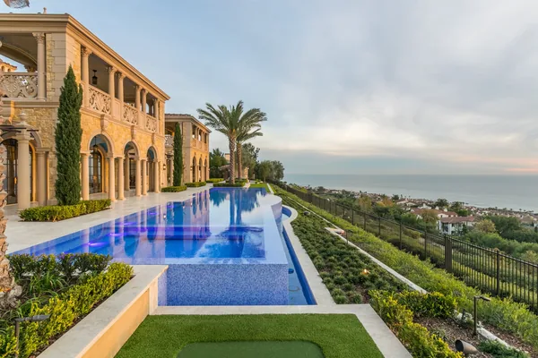 Blue tiled infinity pool beside coastal stone estate in Crystal Cove