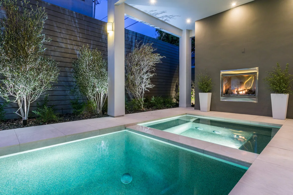 Courtyard pool spa and lit fireplace at dusk