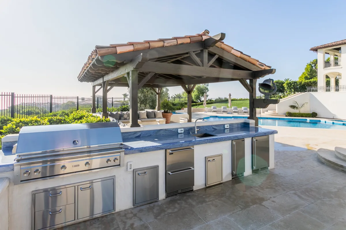 Covered outdoor kitchen with grill and stone counter in Pelican Hill
