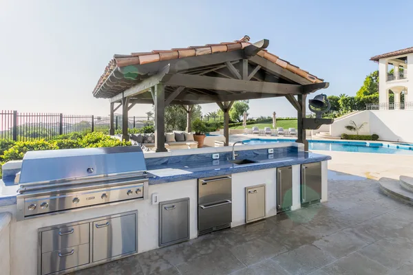 Covered outdoor kitchen with grill and stone counter in Pelican Hill