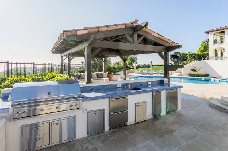 Covered outdoor kitchen with grill and stone counter in Pelican Hill