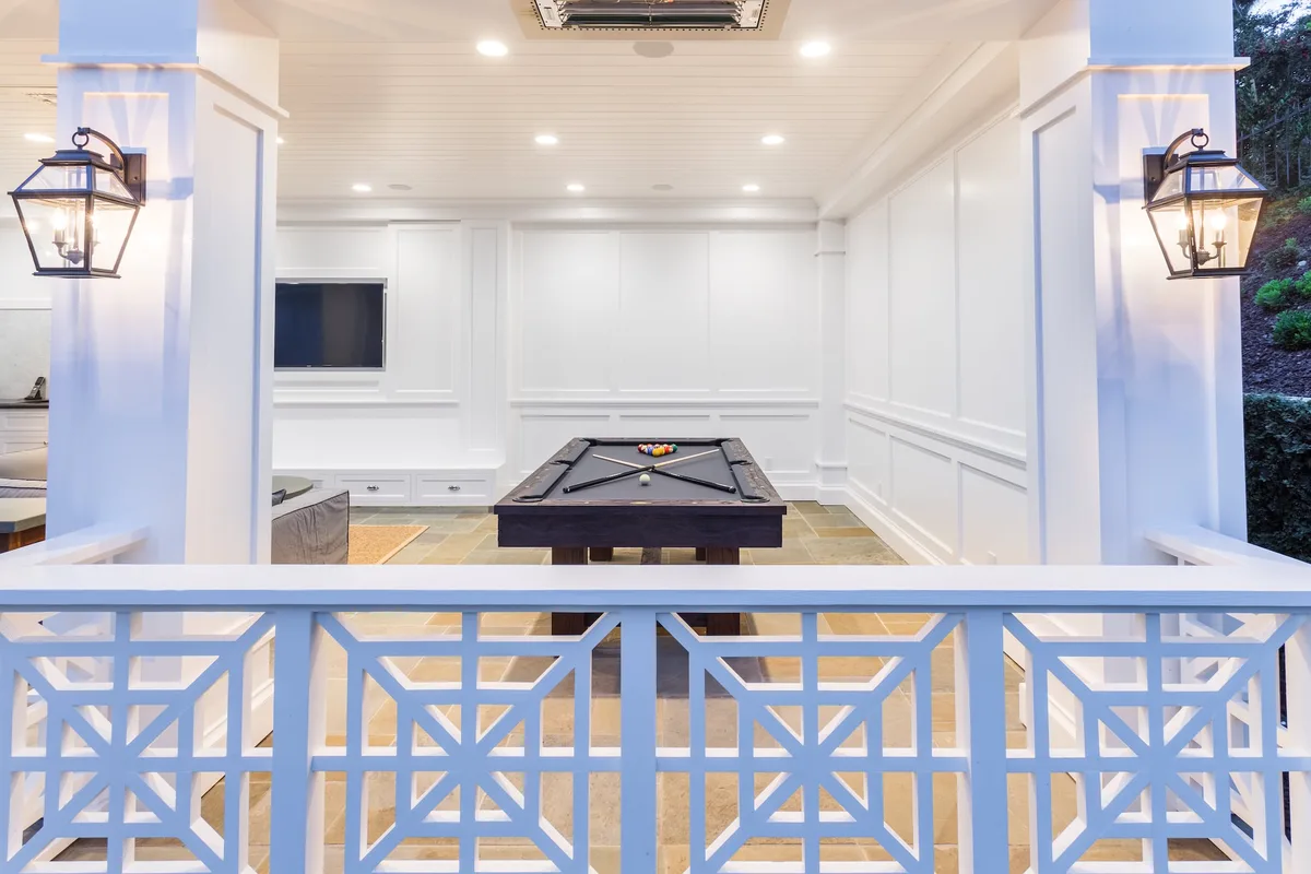Covered pool house game room behind geometric railing
