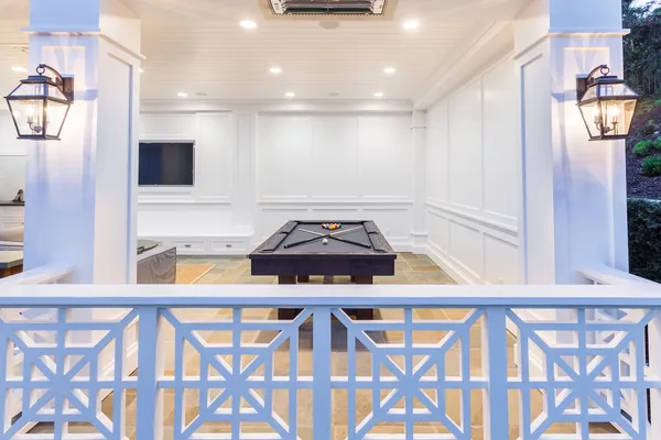 Covered pool house game room behind geometric railing