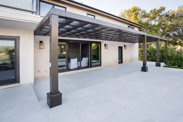 Dark framed pergola over paved patio