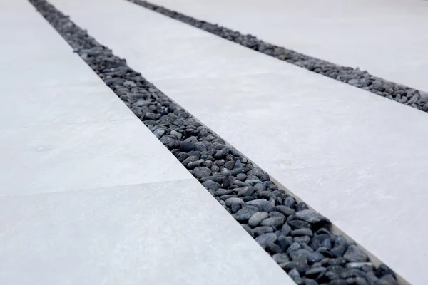 Dark pebble joints between pale paving slabs
