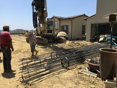 Deep caisson reinforcing cages staged beside drill rig