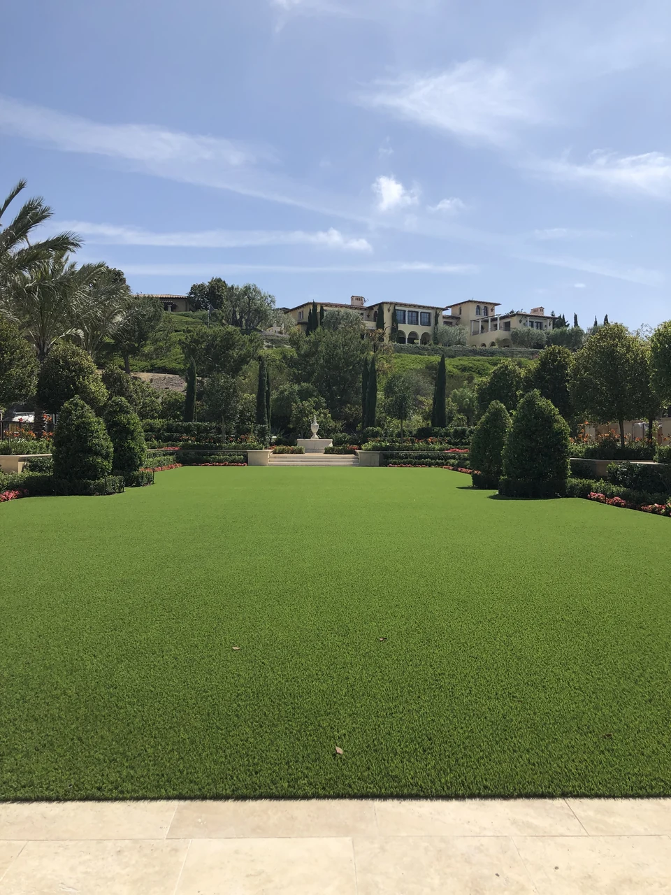 Large rectangular artificial lawn surrounded by formal planting and stone borders