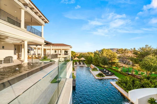 Glass balcony railing overlooking pool and landscaped slope in La Quinta