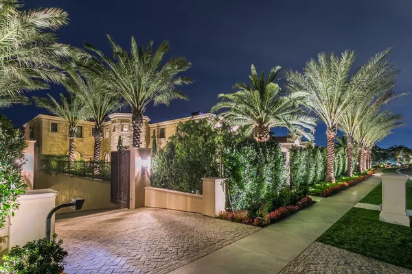 Illuminated gated driveway and palm lined hedge in Crystal Cove