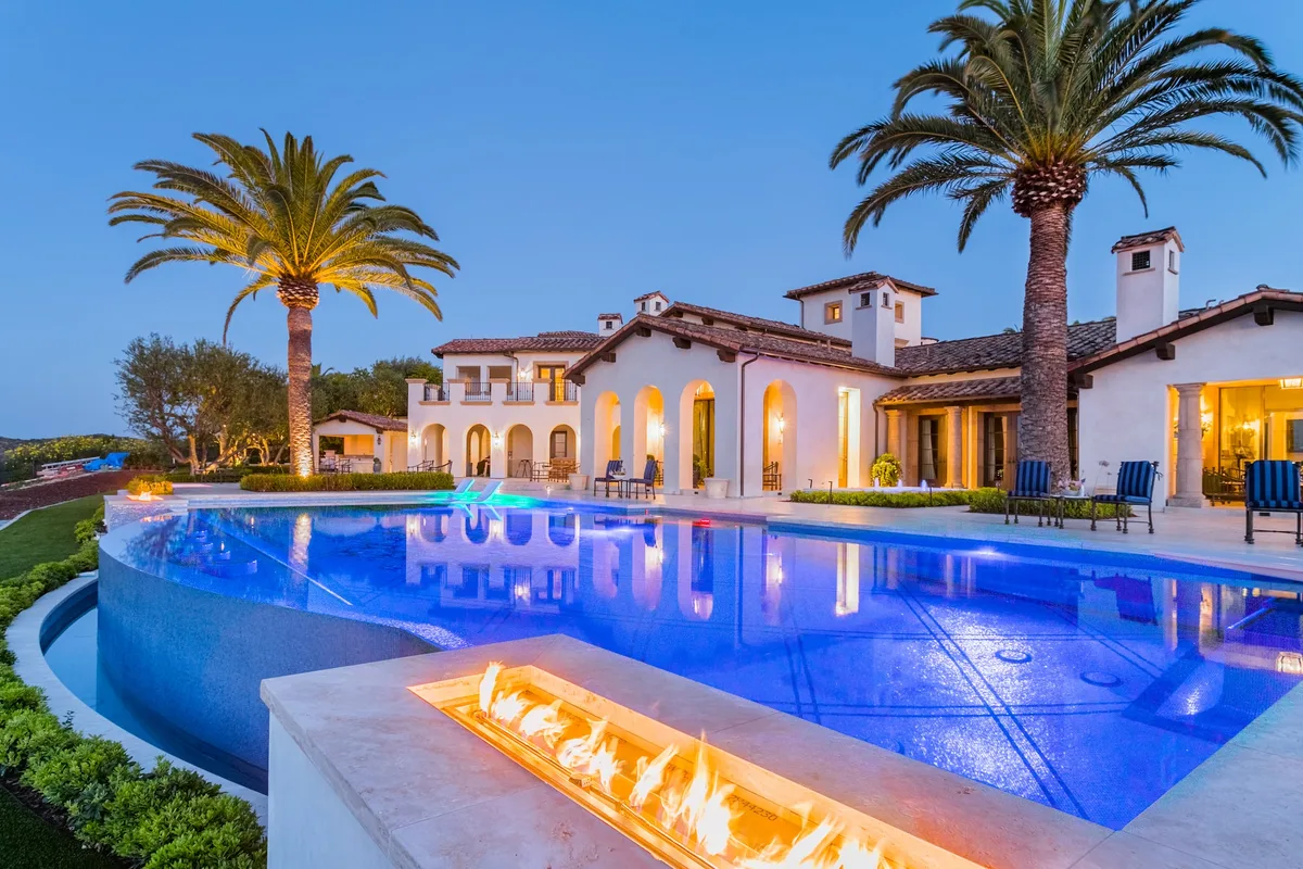 Illuminated infinity pool and linear fire feature at dusk in Irvine