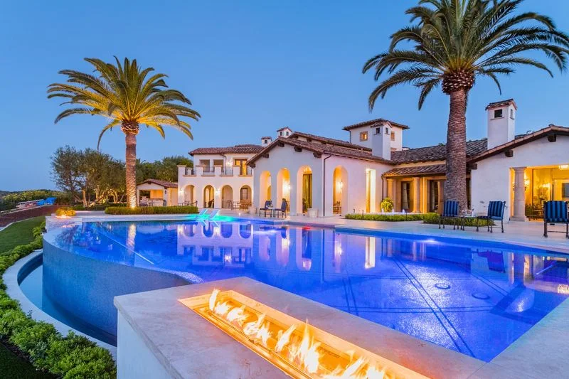 Illuminated infinity pool and linear fire feature at dusk in Irvine