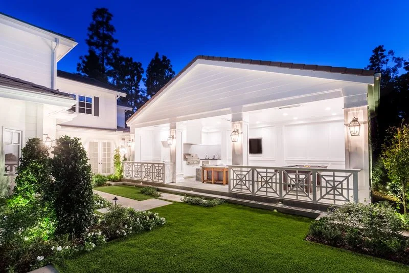 Illuminated pool house and lawn at blue hour