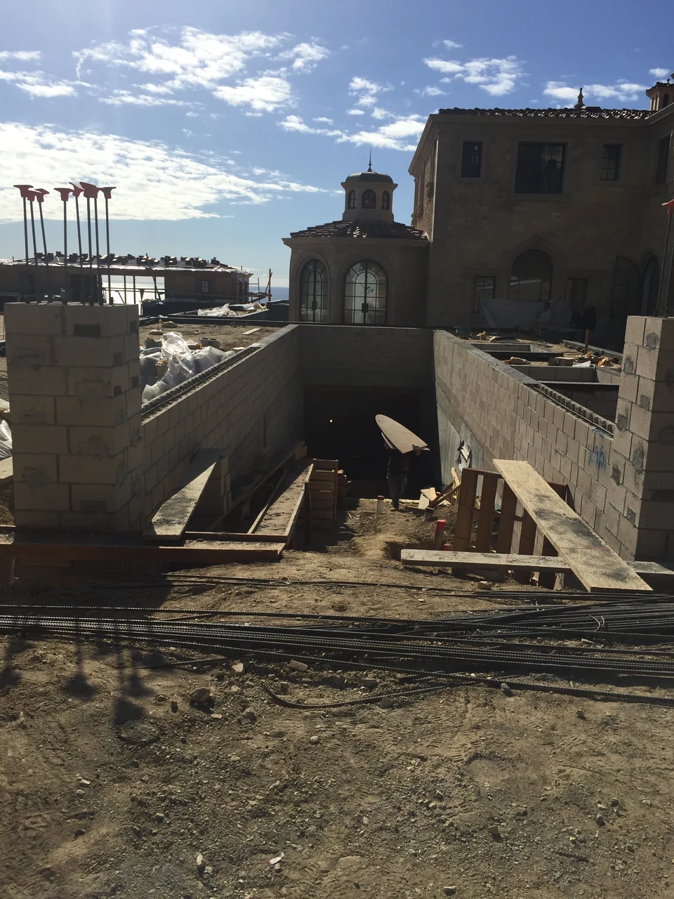 Substantial masonry walls around a lowered area under construction beside the residence