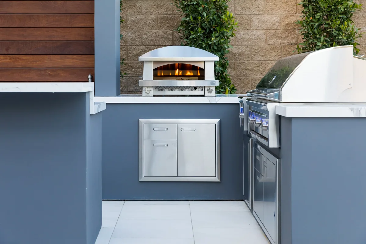 Outdoor kitchen with pizza oven and stainless steel grill