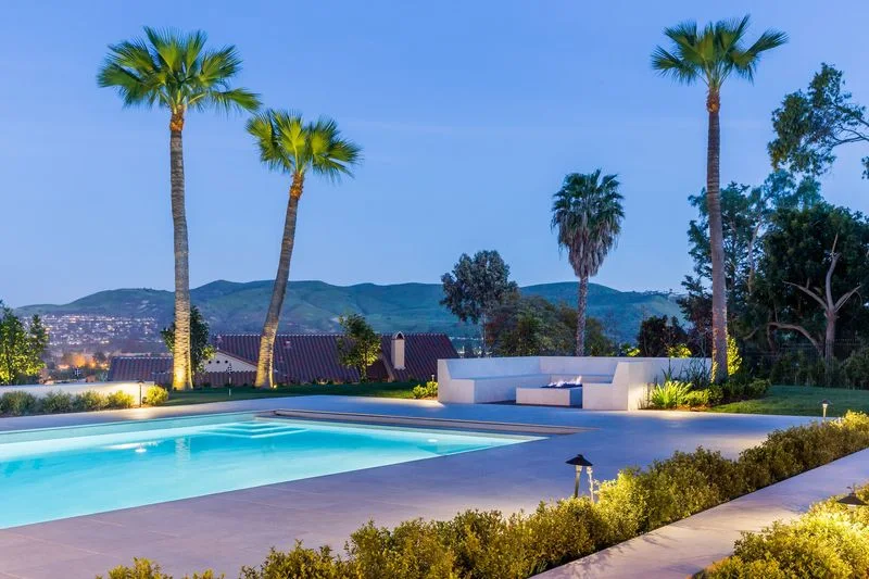 Palm lined pool terrace with evening landscape lighting