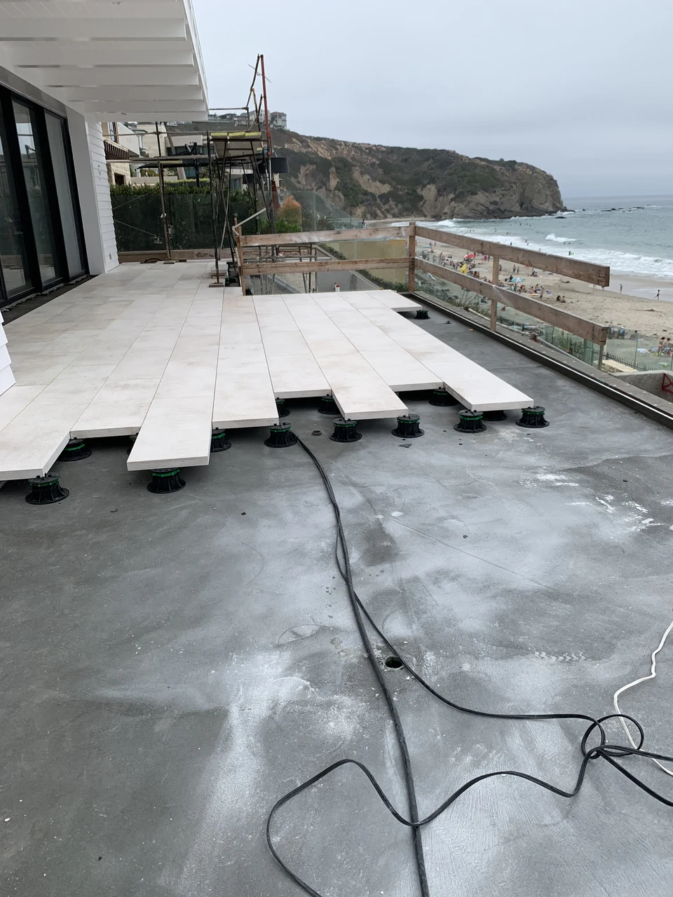 Coastal terrace under construction with pale pavers raised on supports above the exposed base