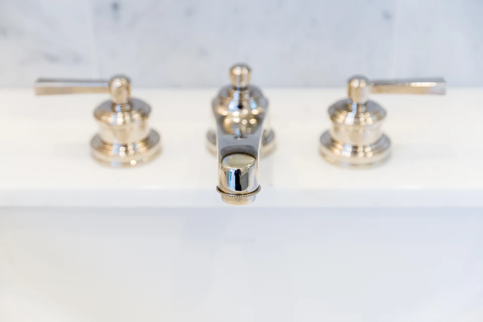 Polished faucet and separate handles on a pale bathroom countertop