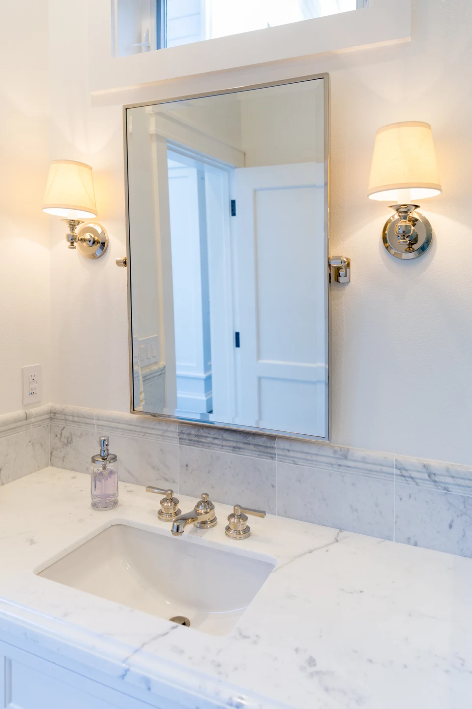 Bathroom vanity with a framed mirror and two shaded wall lights