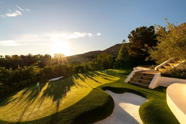 Putting green and practice bunker in evening sunlight in La Quinta
