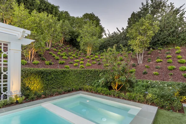 Raised spa with planted slope and clipped hedge