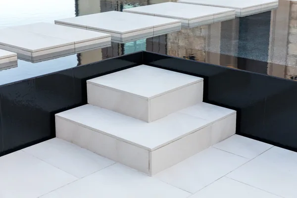 Square tiled spa steps and black pool edge