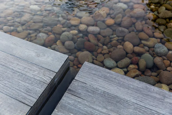 Stone stepping pad joint above river pebble pond