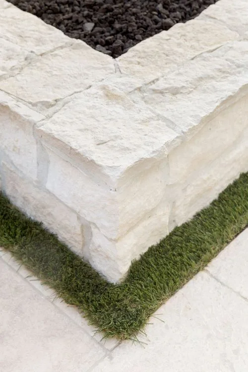 Textured stone fire pit corner and grass border
