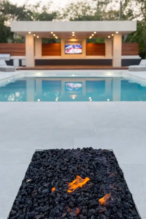 White fire pit with lava rock overlooking pool
