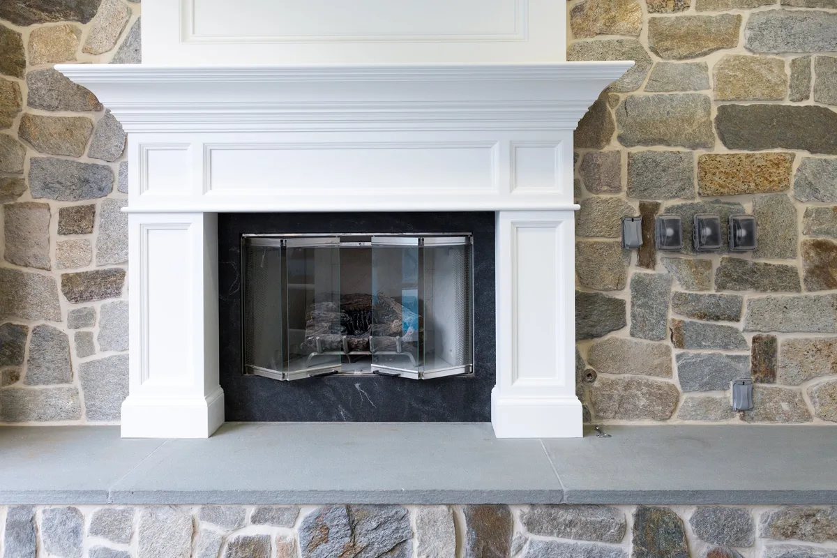 White fireplace mantel with stone facing and gray hearth