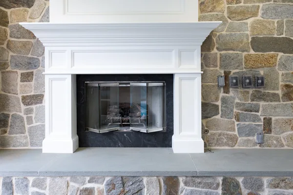 White fireplace mantel with stone facing and gray hearth