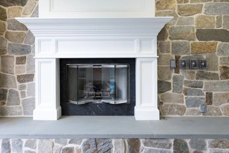White fireplace mantel with stone facing and gray hearth