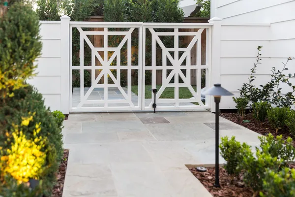 White geometric garden gates and stone entry path