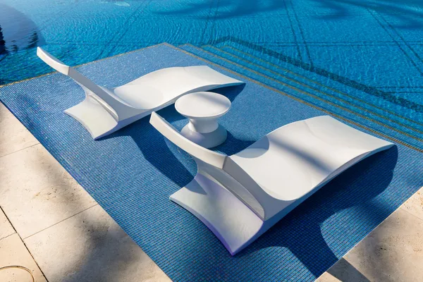 White in pool loungers on blue tiled sun shelf in Irvine