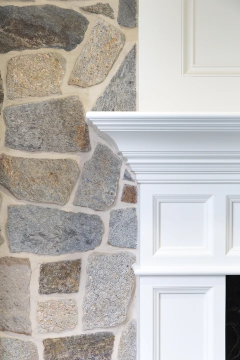 White mantel molding against textured stone facing