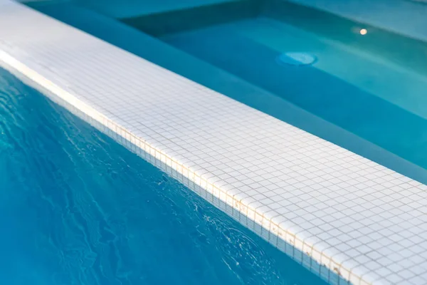 White tiled spa spillway above blue pool water