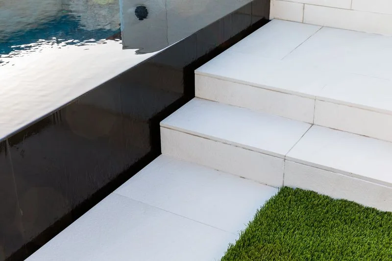 White tiled steps beside a black pool wall