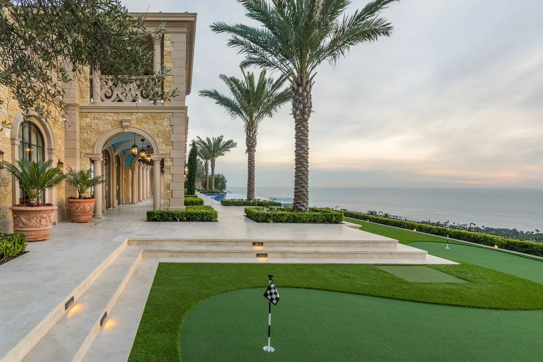 Palms, clipped planting and lawn beside an ocean-facing terrace