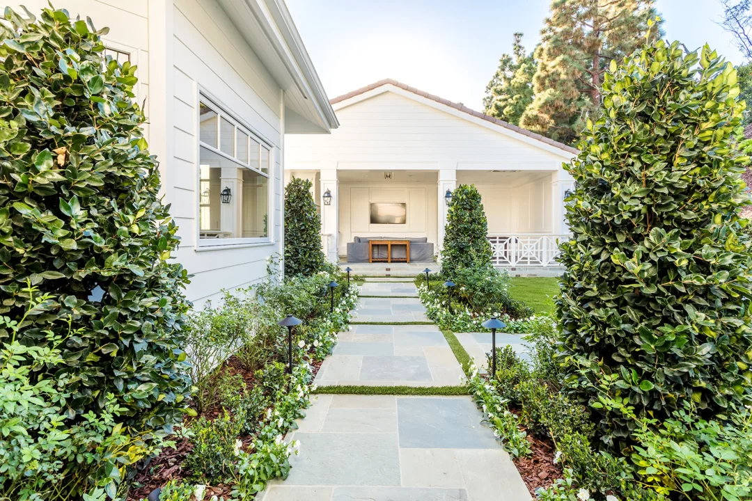 Garden stepping path framed by clipped shrubs and a covered seating area