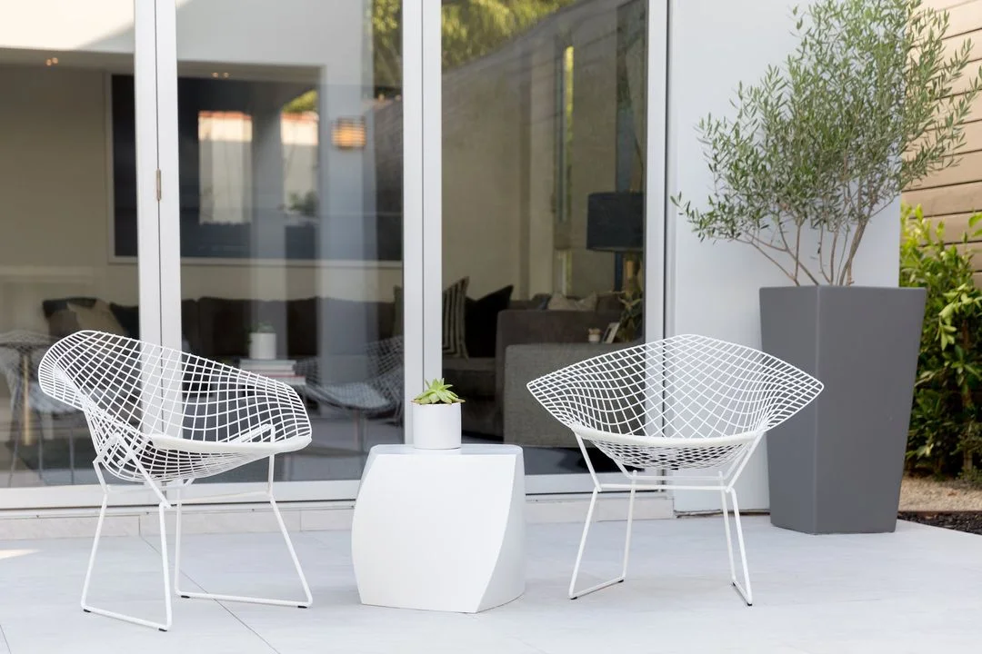 White outdoor chairs beside a planted courtyard container