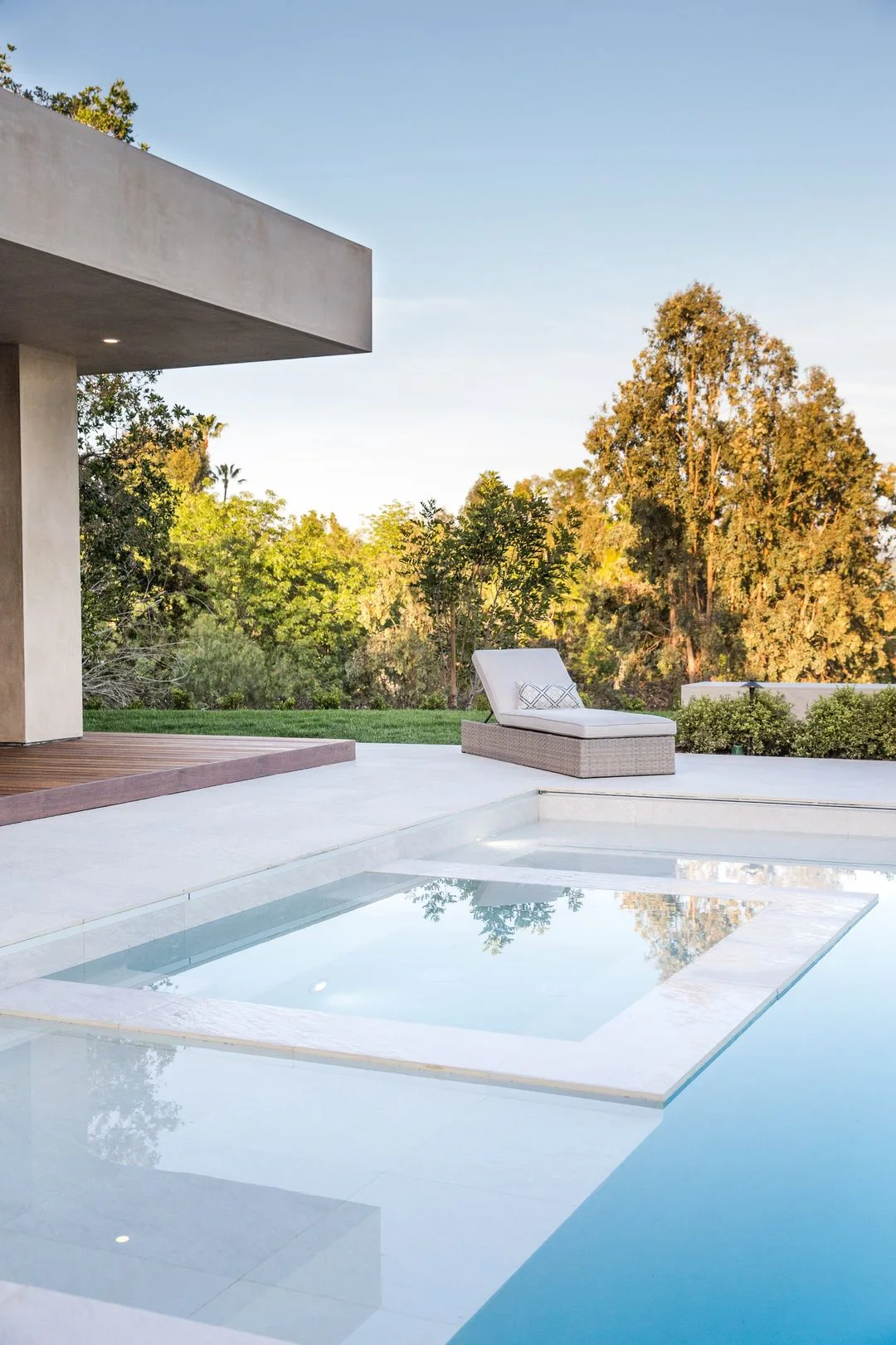 Poolside lounge area beside planting and a timber deck