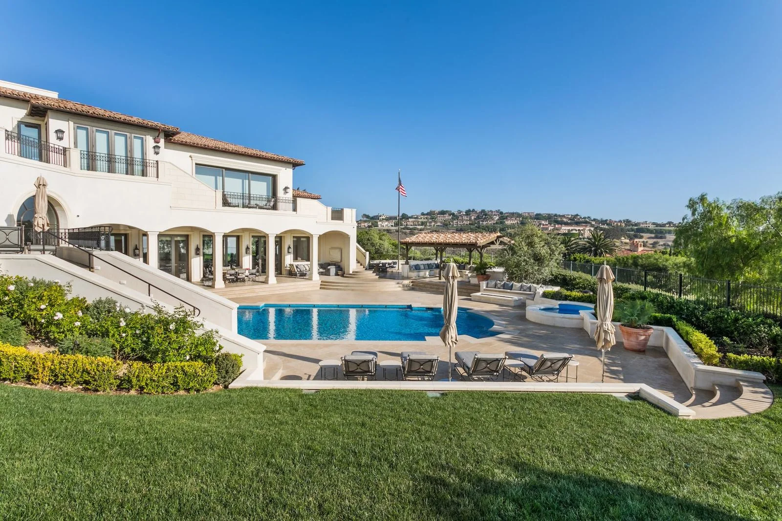 Pelican Hill home overlooking a pool terrace, lawn and landscaped grounds