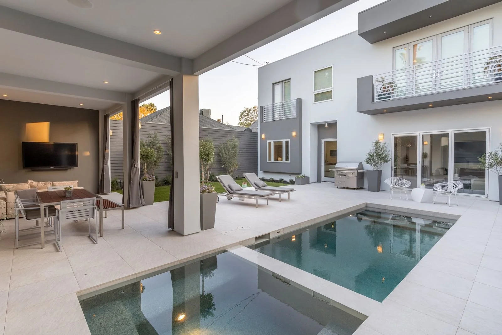 Compact modern pool and spa beside a covered outdoor living room