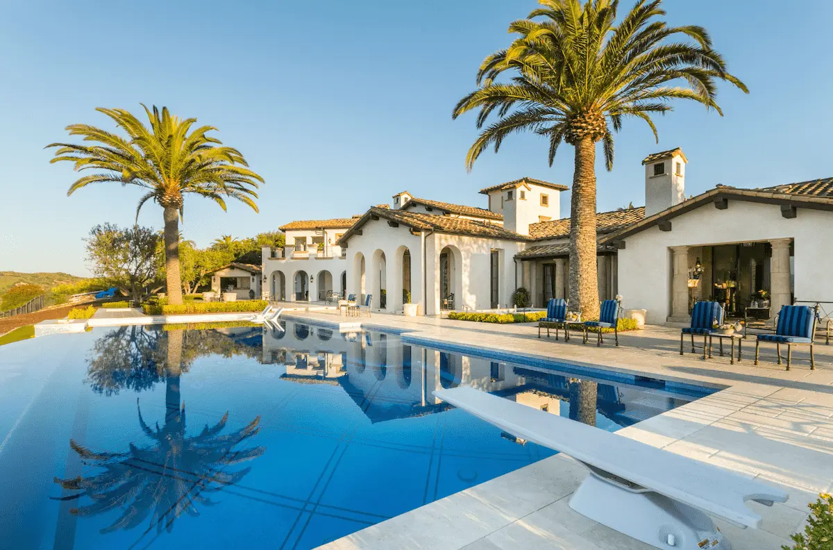 Broad swimming pool and spa with palms beside an Irvine residence