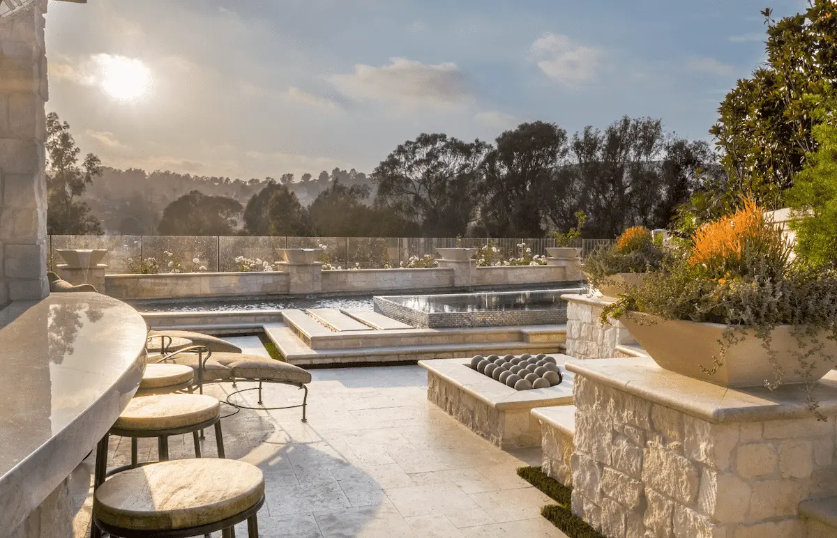 Stone-faced outdoor counter and seating area overlooking a pool and raised spa